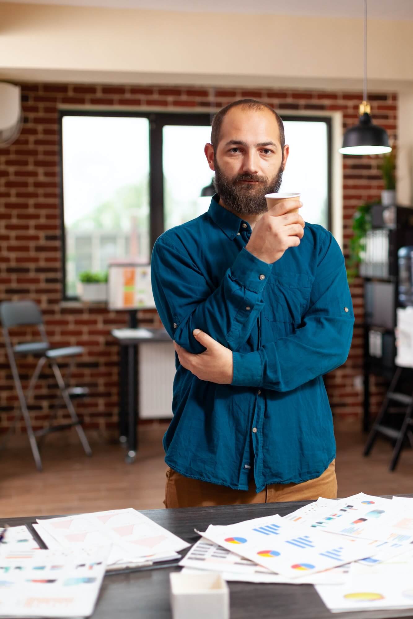 portrait-of-bookkeeper-man-holding-cup-of-coffee-standing-in-startup-company-office.jpg